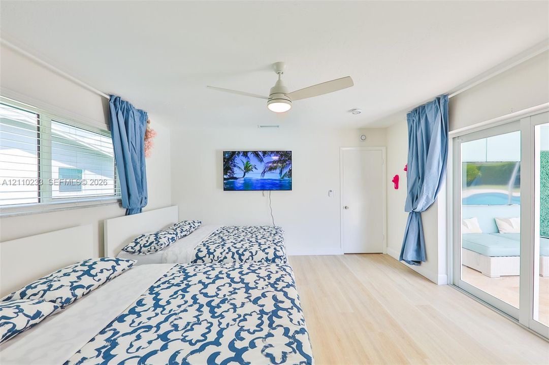 Light-toned wood-finish flooring, ceiling fan with integrated lighting, and glass sliding doors providing exterior exposure