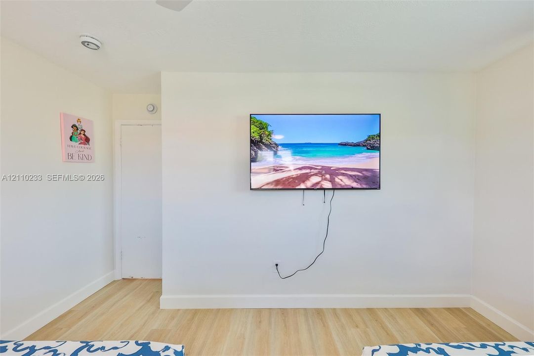 Neutral-toned interior wall featuring wood-finish flooring and a white swing-style door