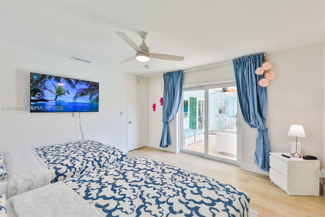 Light-toned wood-finish flooring, ceiling fan with integrated lighting, and glass sliding doors