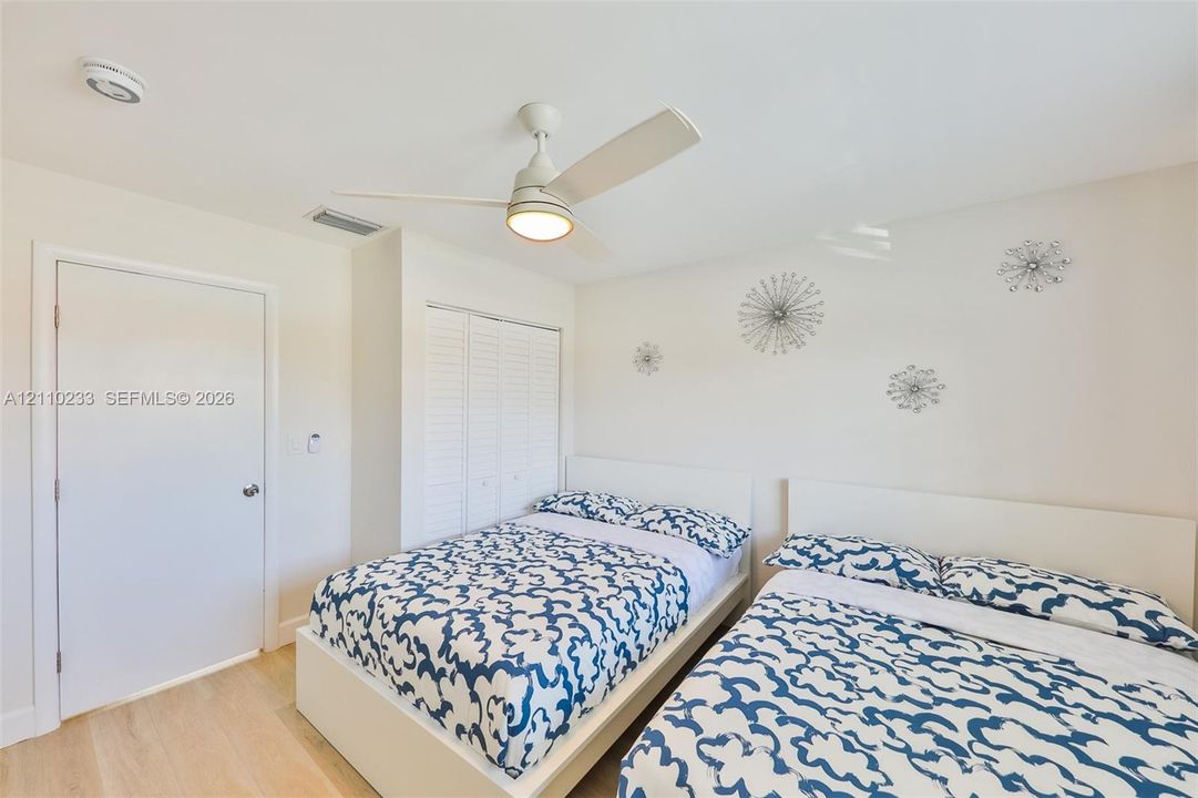 Interior space featuring light-tone wood-finish flooring, a white ceiling fan with integrated lighting, and a closet with white louvered bi-fold doors