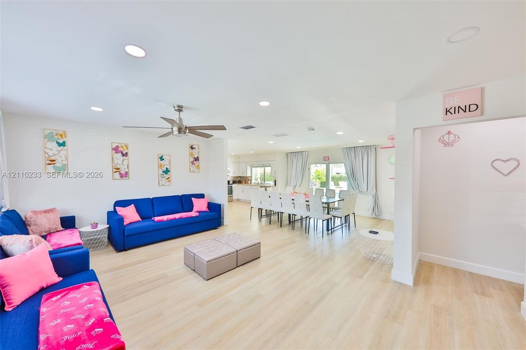Open-concept interior featuring light wood-finish flooring, recessed lighting, and a neutral color palette with an integrated ceiling fan