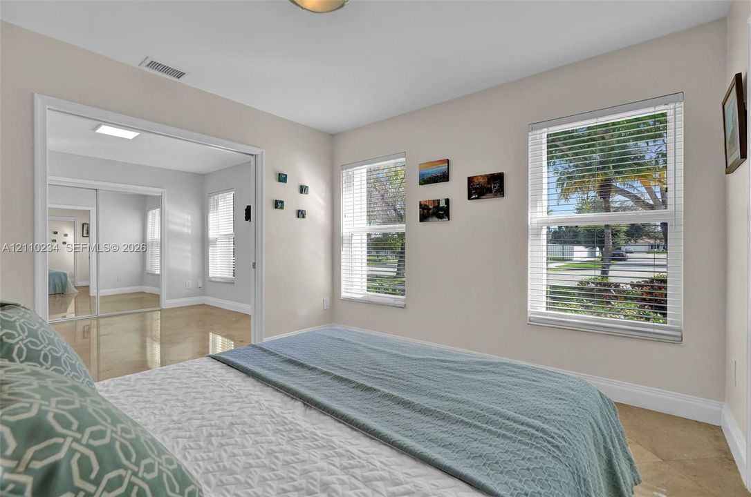 Neutral-toned interior featuring oversized tile flooring, large dual-pane windows with integrated blinds, and mirrored closet doors