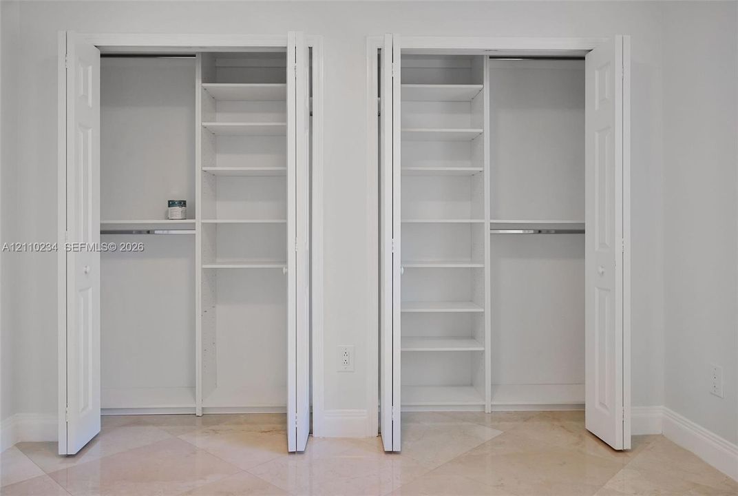 Dual closets featuring white bi-fold doors, built-in shelving units, and integrated clothing rods