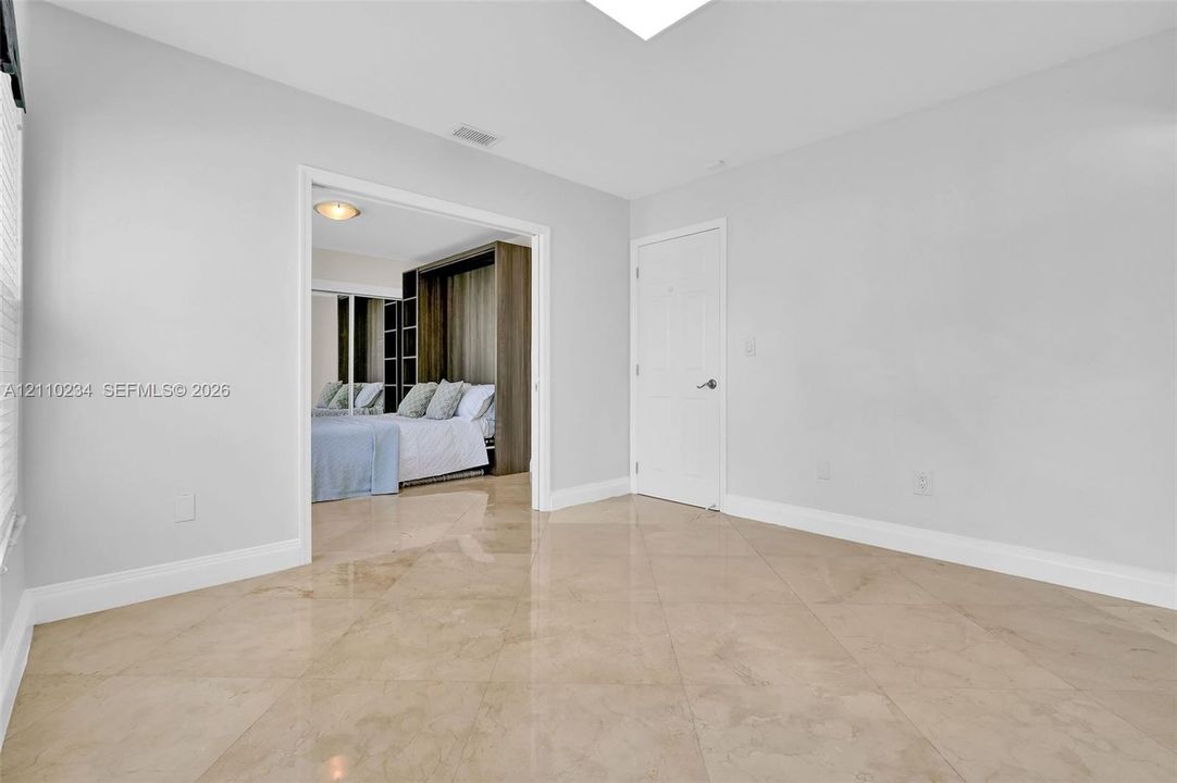 Large-format neutral tile flooring, smooth ceilings, and white interior doors