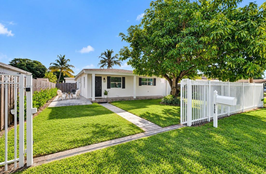 Single-story exterior featuring ample parking, gated entry, manicured lawn, and mature tree canopy