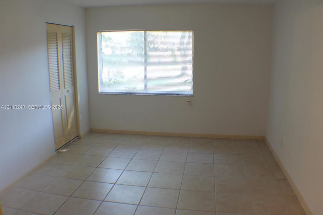 Interior space featuring large-format ceramic tile flooring, a horizontal sliding window, and a louvered bi-fold closet door