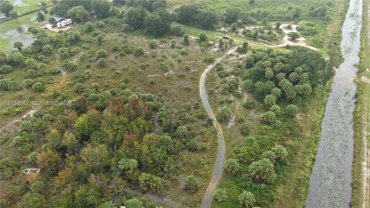 Expansive acreage featuring mature trees, native vegetation, natural landscape contours, and a bordered waterway