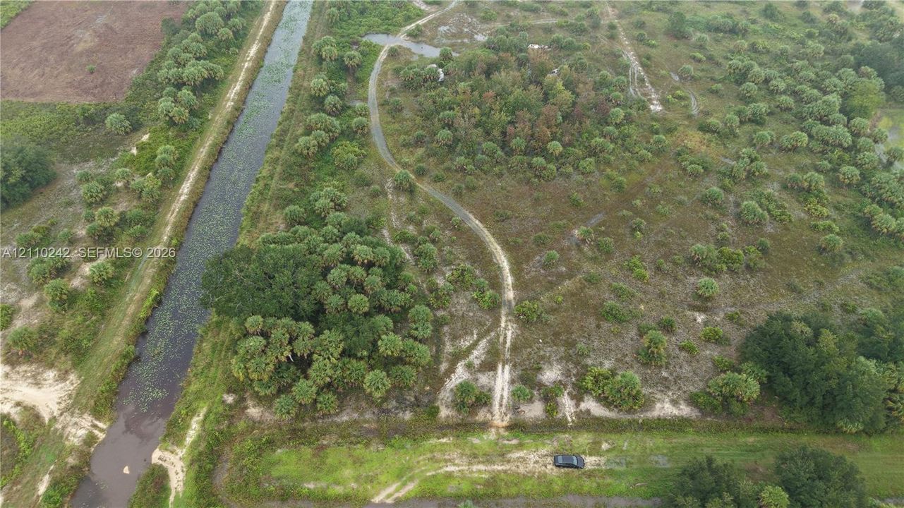 Expansive acreage featuring native vegetation, wooded clusters, natural terrain, and direct water frontage along a canal