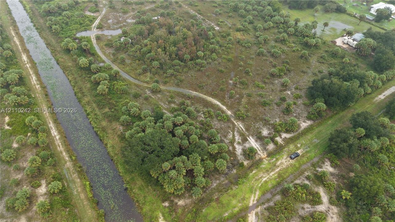 Expansive parcel of land featuring natural vegetation, native trees, and bordering canal frontage