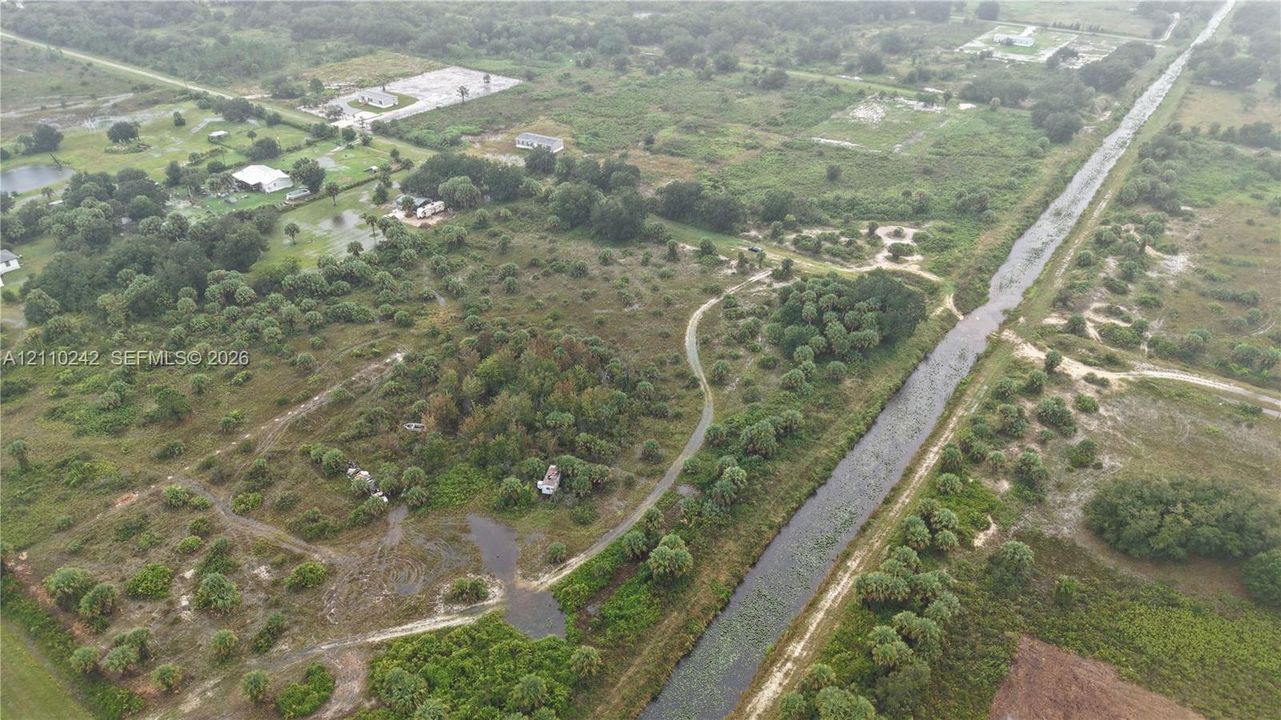 Expansive acreage featuring natural vegetation, native tree clusters, and bordering canal
