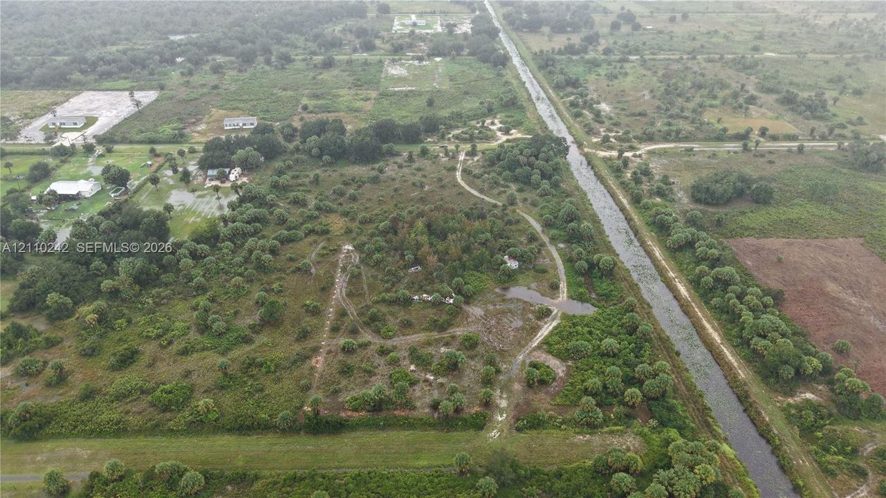 Expansive acreage featuring established native vegetation, mature tree clusters, and canal-front positioning