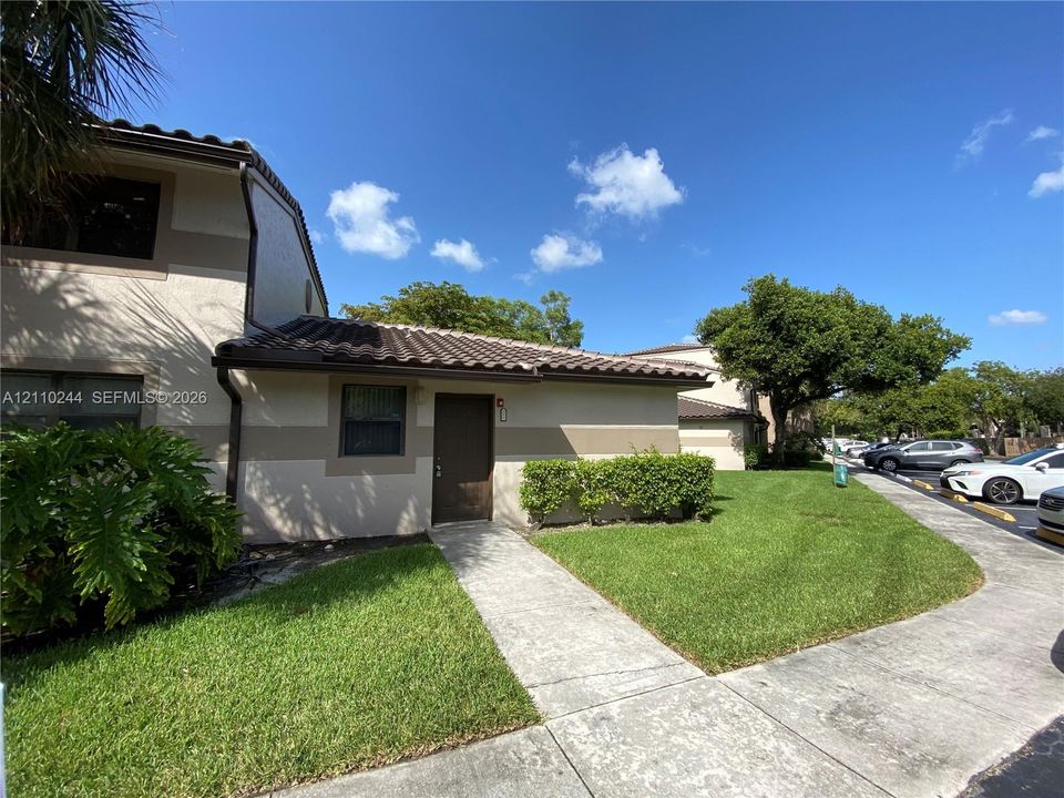 Two-story exterior featuring a neutral stucco facade, a dark-toned tile roof, and a concrete entryway path