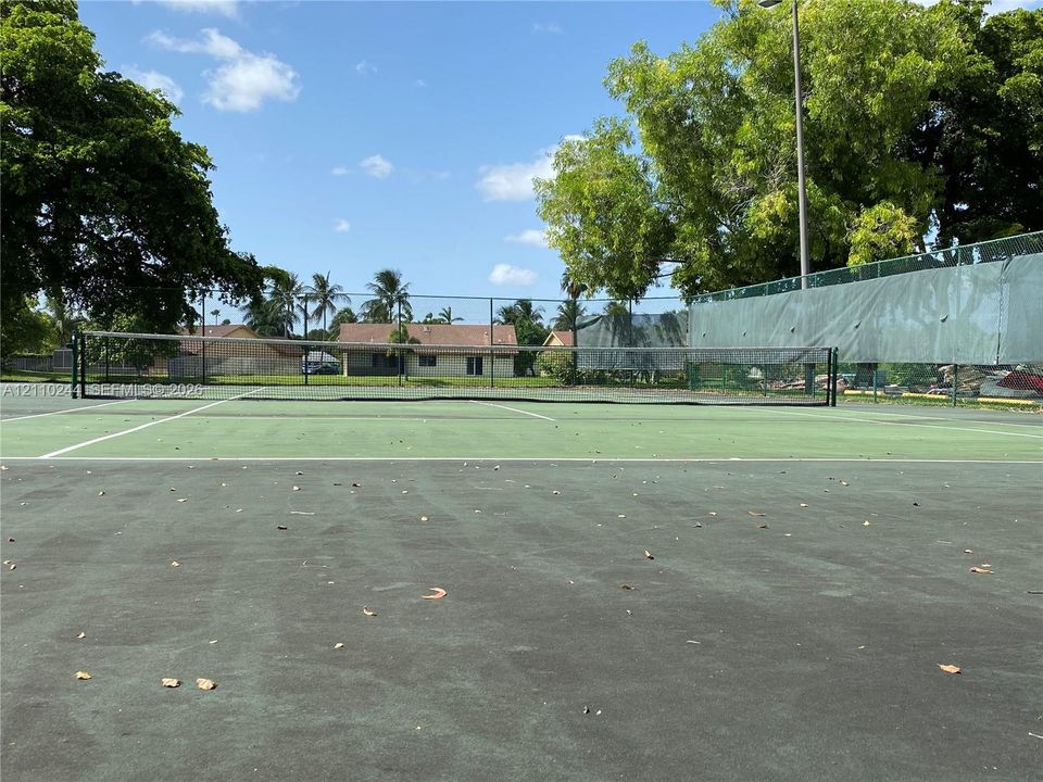 Tennis court featuring a paved surface, perimeter fencing, and exterior pole lighting