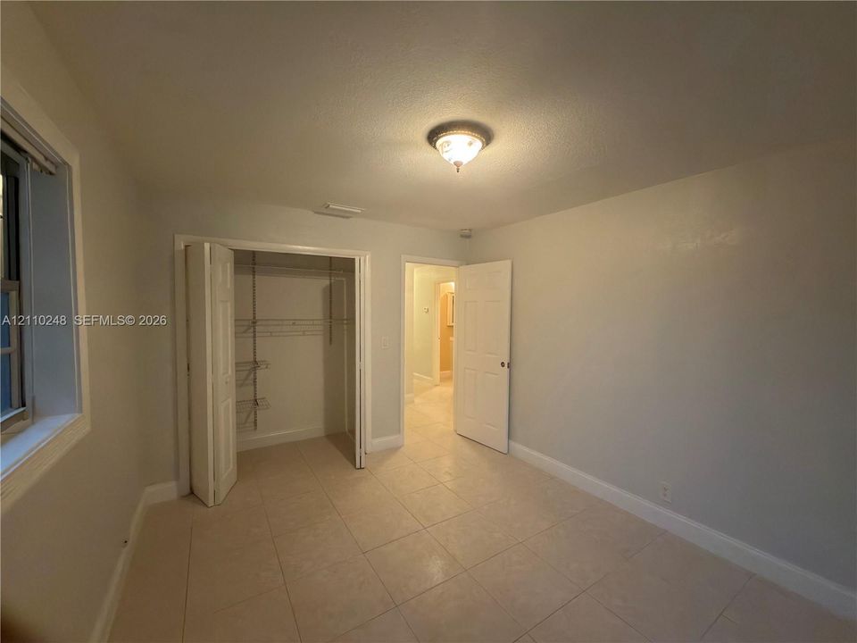 Tile flooring, recessed ceiling lighting, and a bi-fold door closet with built-in shelving
