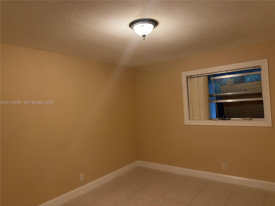 Neutral wall finishes, large-format tile flooring, flush-mount decorative ceiling fixture, and horizontal window blinds