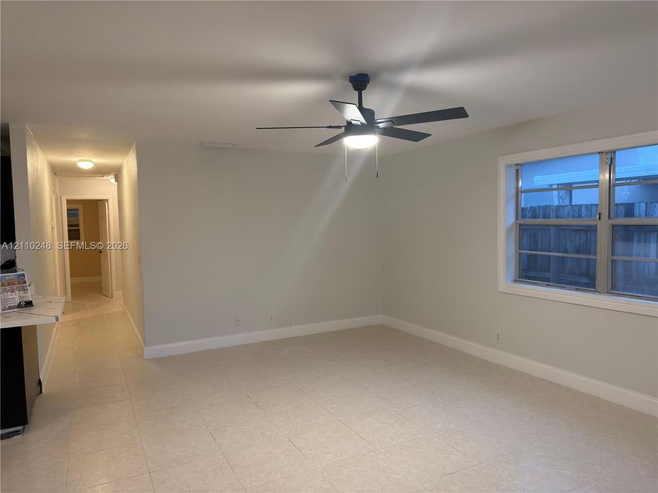 Interior space featuring light-toned tile flooring, neutral wall paint, a multi-blade ceiling fan with integrated light fixture, and horizontal sliding windows