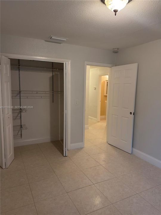 Neutral-toned tile flooring, closet with built-in wire shelving, and six-panel interior doors