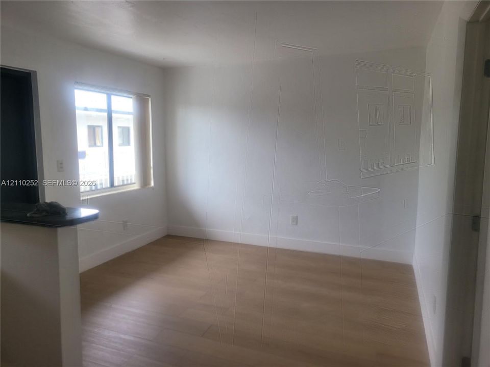 Interior space featuring wood-finish flooring, white walls, and a single-pane window