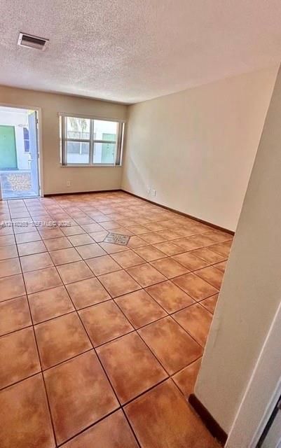 Interior space featuring ceramic tile flooring, neutral wall tones, a large window, and an exterior door