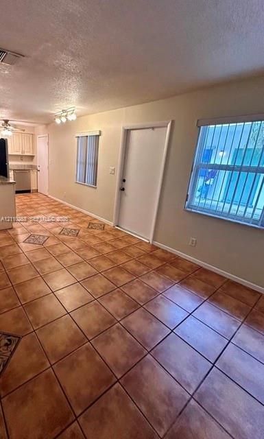 Ceramic tile flooring with decorative inlay accents, multi-light ceiling fixture, and dual windows with integrated vertical blinds