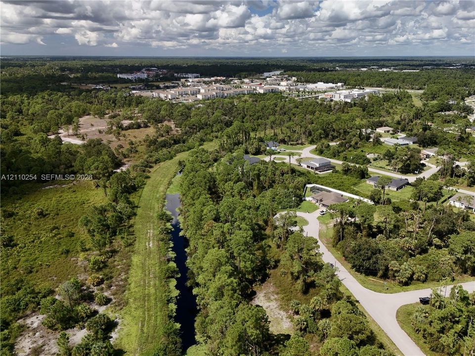 Aerial perspective featuring extensive wooded acreage, native vegetation, and a natural waterway