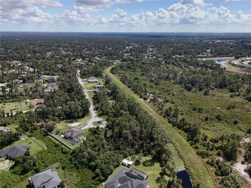 Aerial perspective featuring expansive wooded acreage and a linear waterway bordering the property grounds