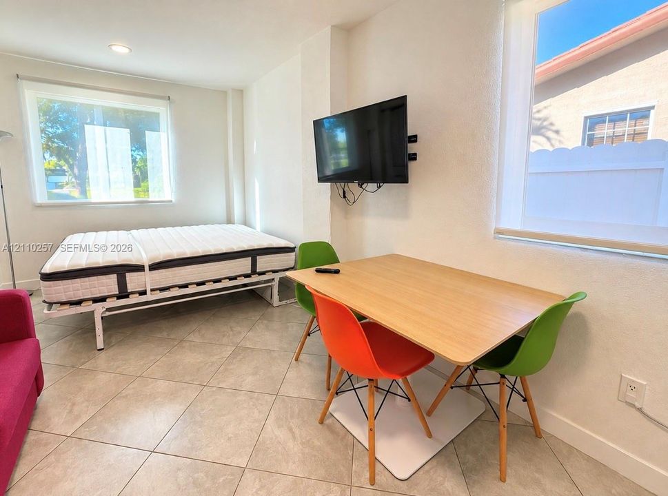 Neutral-tone tile flooring, recessed ceiling lighting, and large windows with integrated roller shades