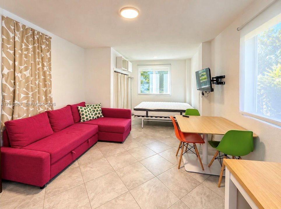 Neutral tile flooring, flush-mount ceiling lighting, dual windows, and wall-mounted television hardware