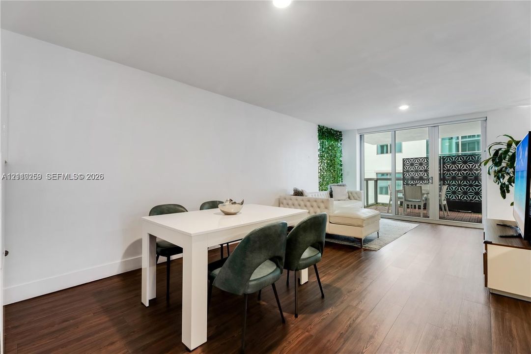 Living area featuring wood-finish flooring, recessed lighting, and expansive floor-to-ceiling glass sliding doors leading to a private balcony