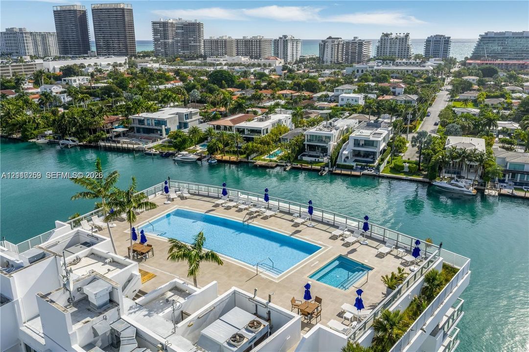 Rooftop terrace featuring a rectangular swimming pool, integrated spa, paved sun deck, and metal railings overlooking the waterway