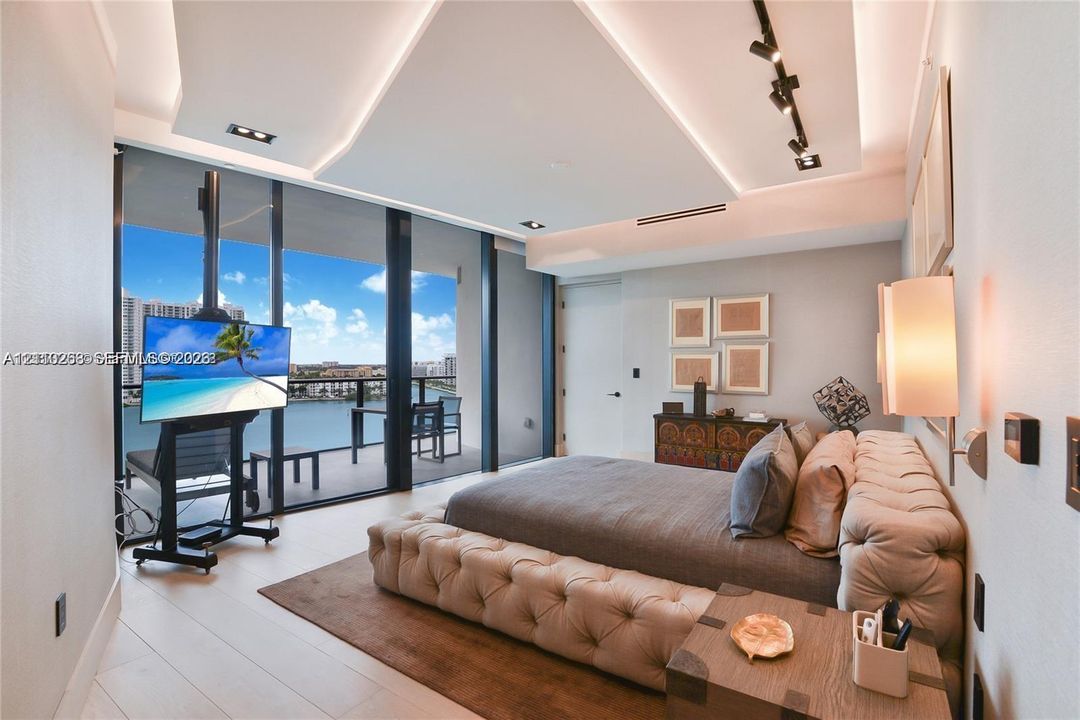 Floor-to-ceiling glass wall, recessed tray ceiling with accent lighting, track lighting, and a private balcony
