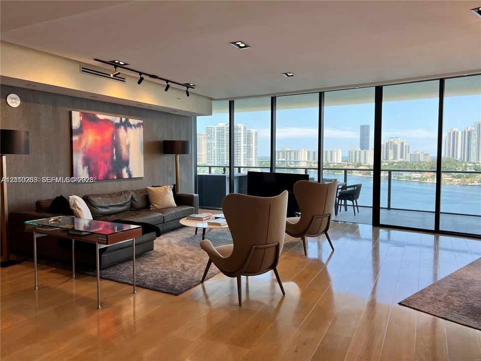 Floor-to-ceiling glass walls, wood-finish flooring, recessed lighting, track lighting, and a private balcony