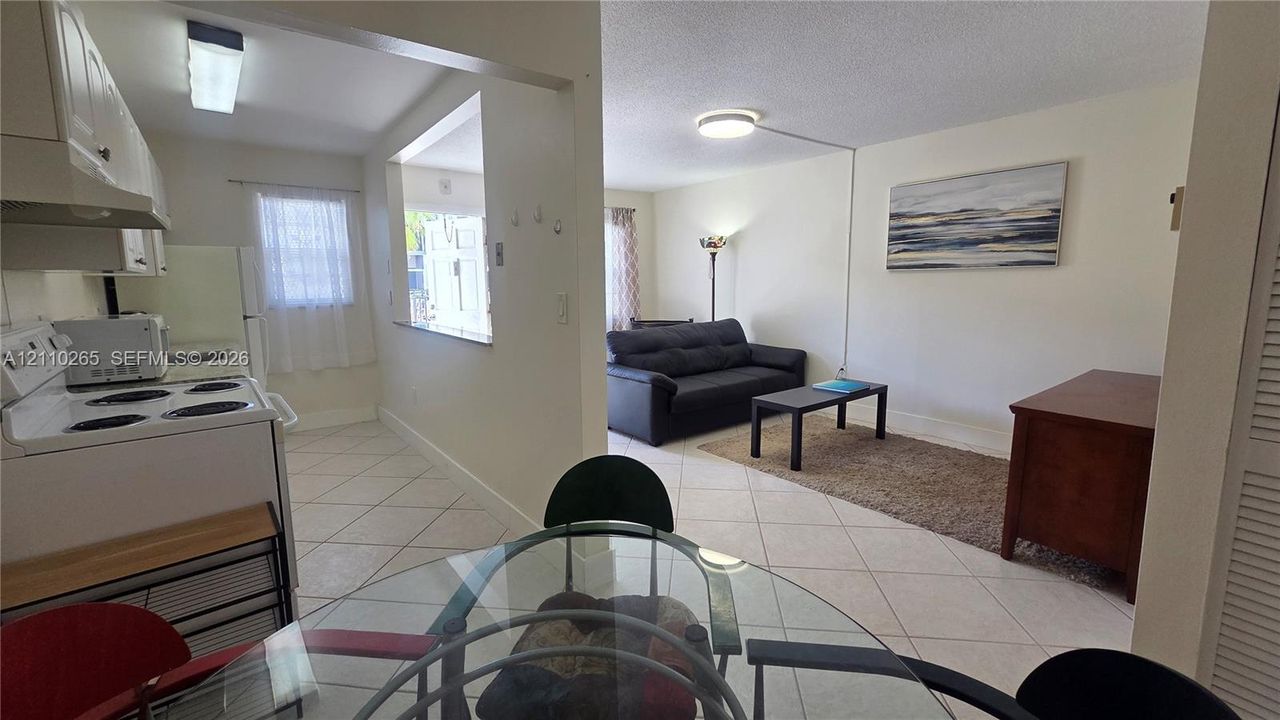 Ceramic tile flooring throughout, white cabinetry, and a kitchen pass-through window