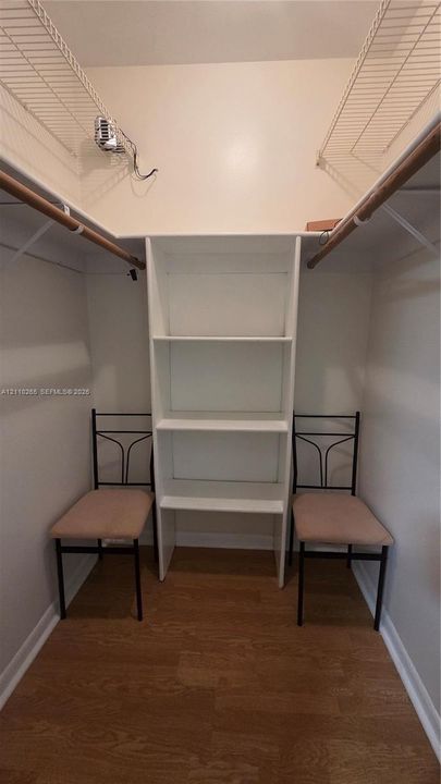 Walk-in closet featuring wood-finish flooring, built-in shelving unit, and dual-level wire hanging rods
