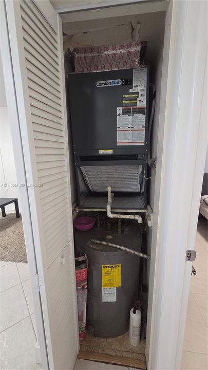Utility closet housing a ComfortStar air handler and an upright water heater behind louvered bi-fold doors