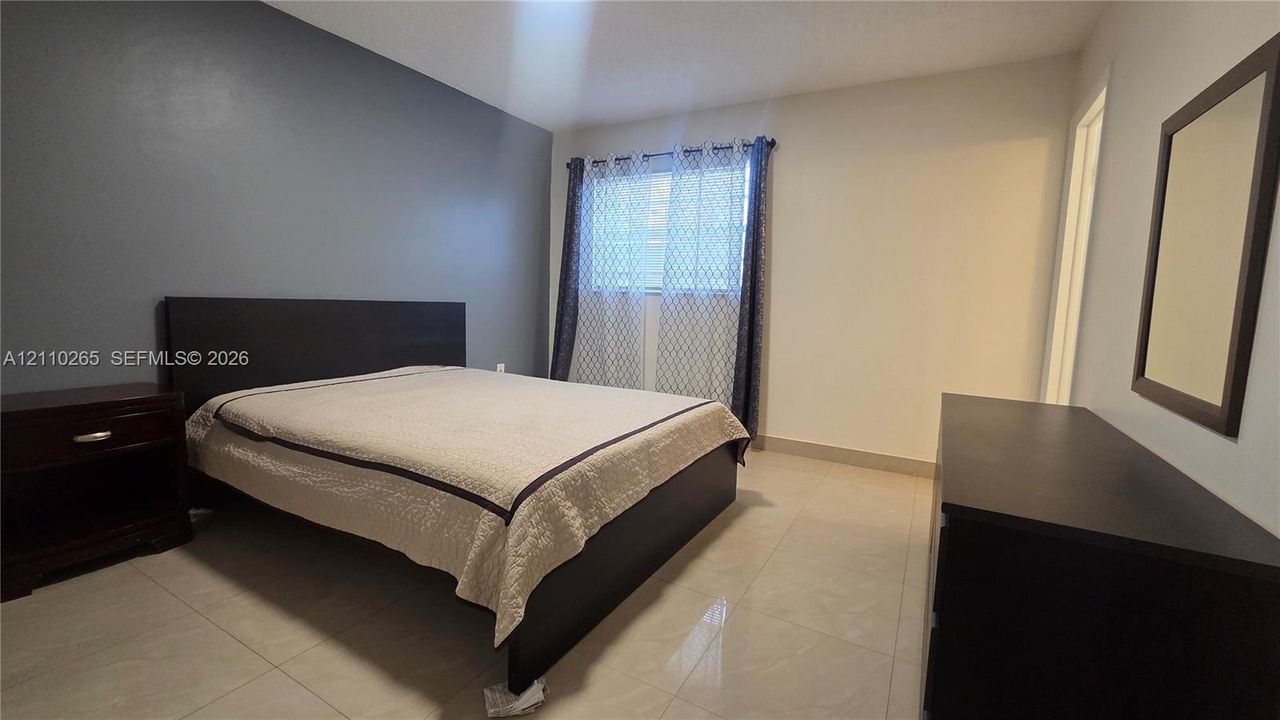 Interior space featuring light-toned tile flooring, neutral wall paint, and a dark-toned accent wall
