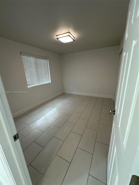 Neutral-toned ceramic tile flooring, square flush-mount ceiling lighting, and horizontal window blinds