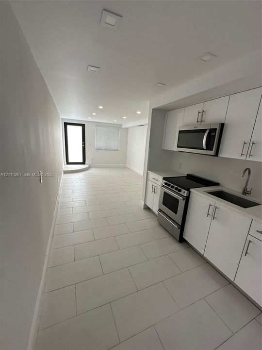 Kitchen featuring white cabinetry with metallic hardware, stainless steel appliances, and tile flooring