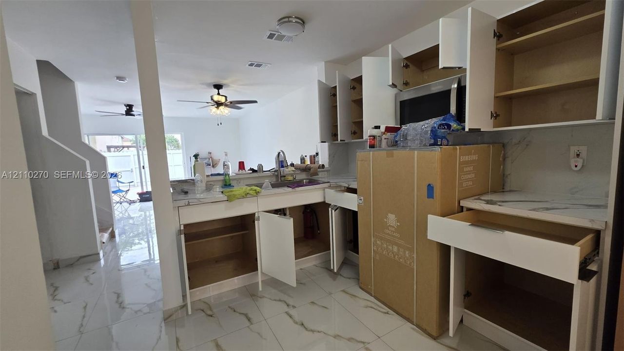 Kitchen featuring white cabinetry, stone-finish countertops, large-format tile flooring, a built-in microwave, and recessed ceiling lighting