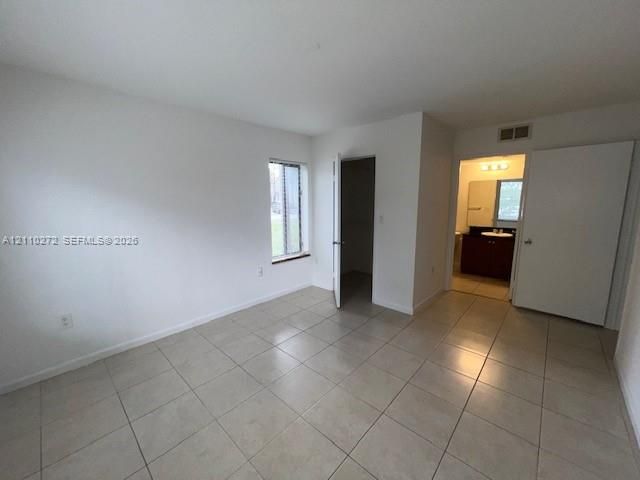 Neutral-toned ceramic tile flooring, interior door leading to a walk-in closet, and a single-pane window