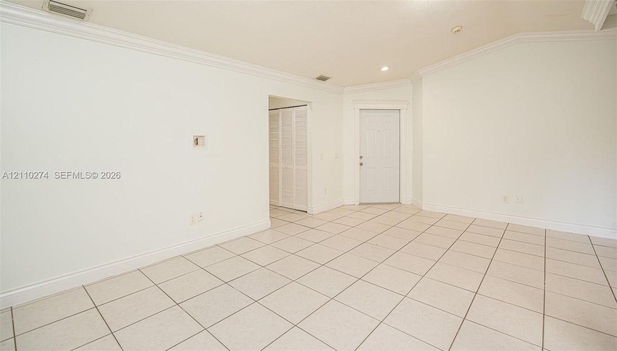 Vaulted ceilings, large-format tile flooring, crown molding, and louvered bifold closet doors
