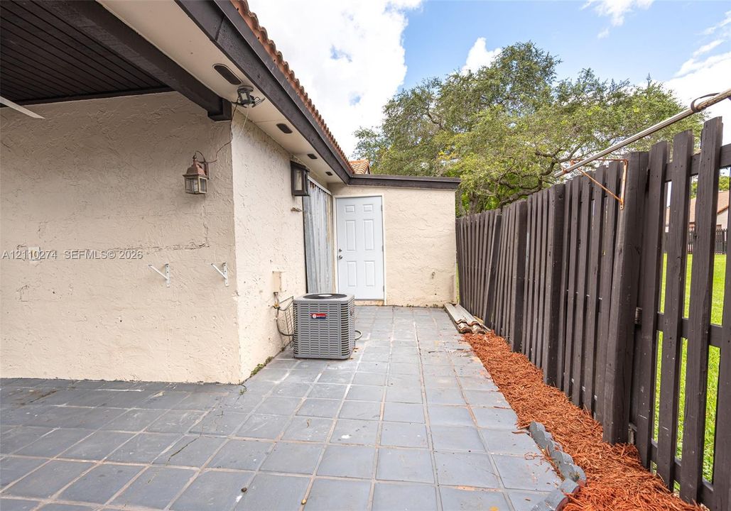 Covered patio featuring tiled flooring, stucco exterior walls, and a wood-slat privacy fence