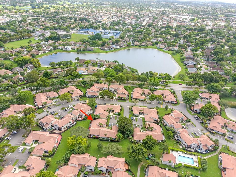 Aerial perspective of a multi-unit residential property featuring tile roofing, stucco exterior finishes, and established landscaping