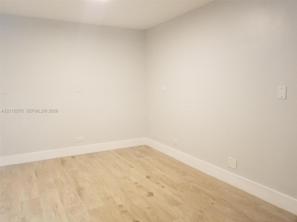 Neutral-toned interior room featuring wood-finish flooring and matte paint finish