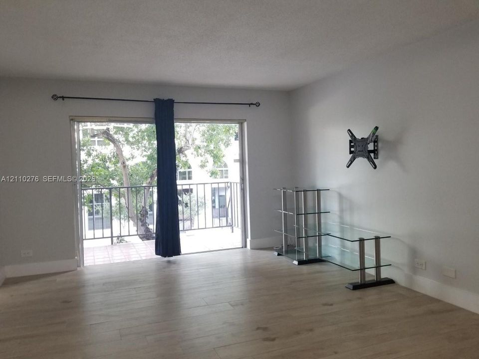 Interior space featuring wood-finish flooring, sliding glass door, and a metal-railed balcony