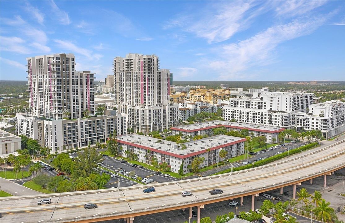 Aerial perspective of a high-rise residential complex featuring private balconies, surface-level parking, and landscaped grounds