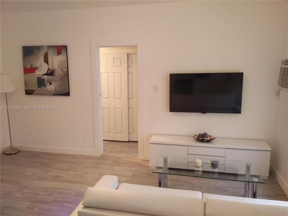 Wood-finish flooring, white panel door, and wall-mounted central heating/cooling unit