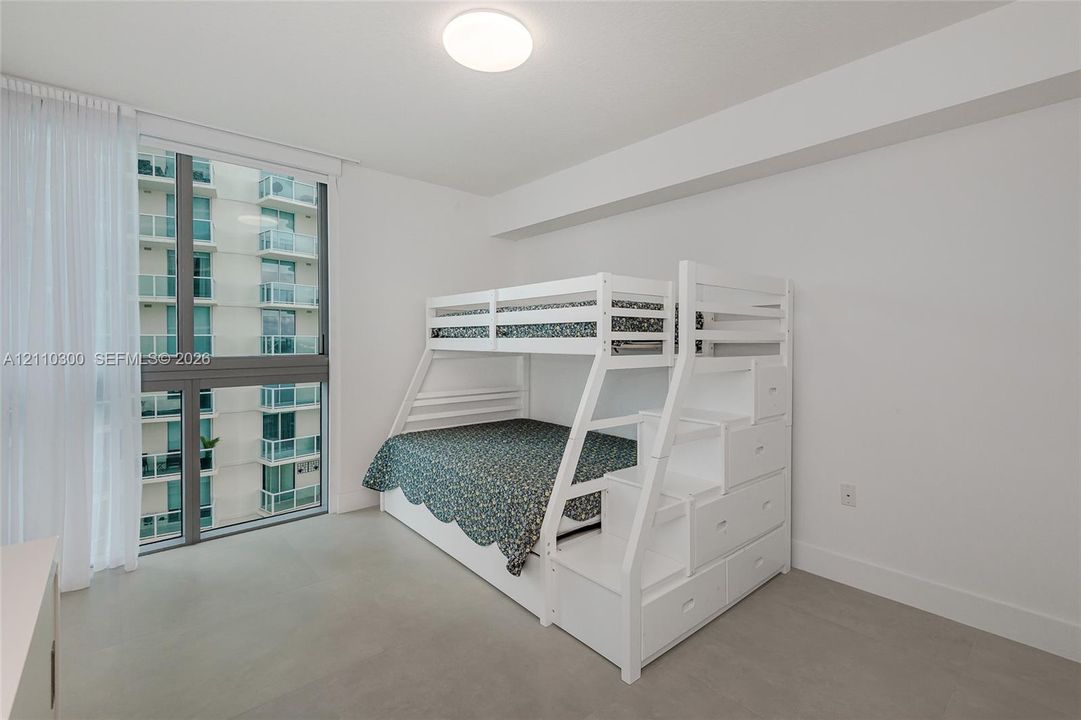 Bedroom 3. Floor-to-ceiling windows featuring metal framing, flush-mount overhead lighting, and neutral-tone flooring