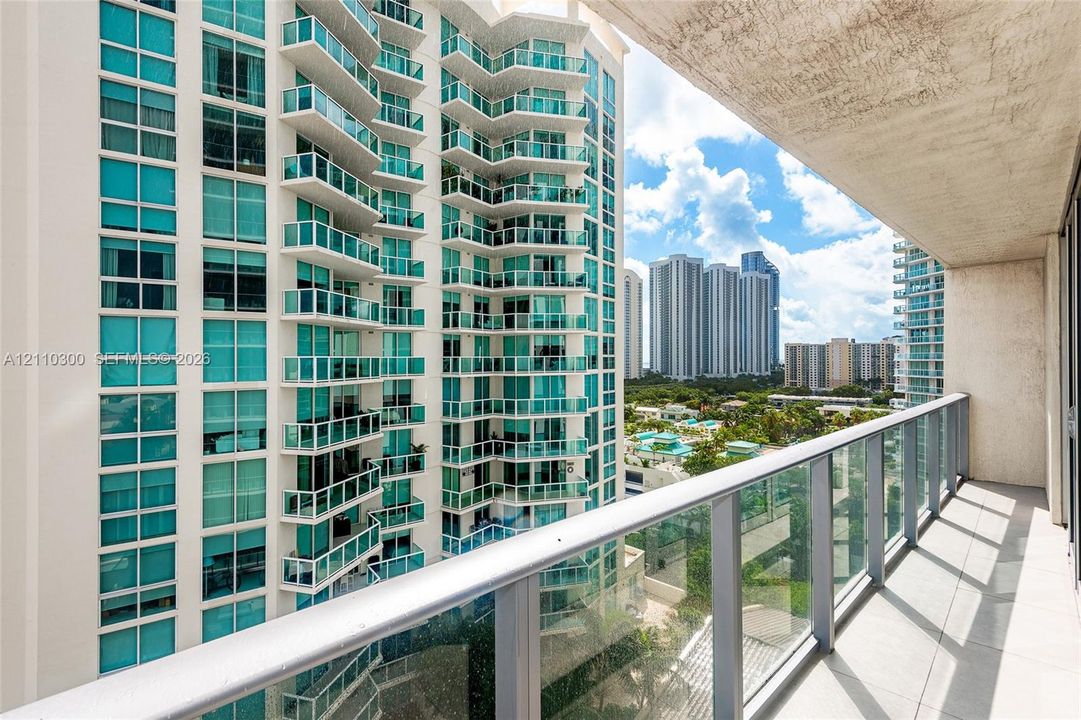 Covered balcony featuring tile flooring and a glass-paneled railing