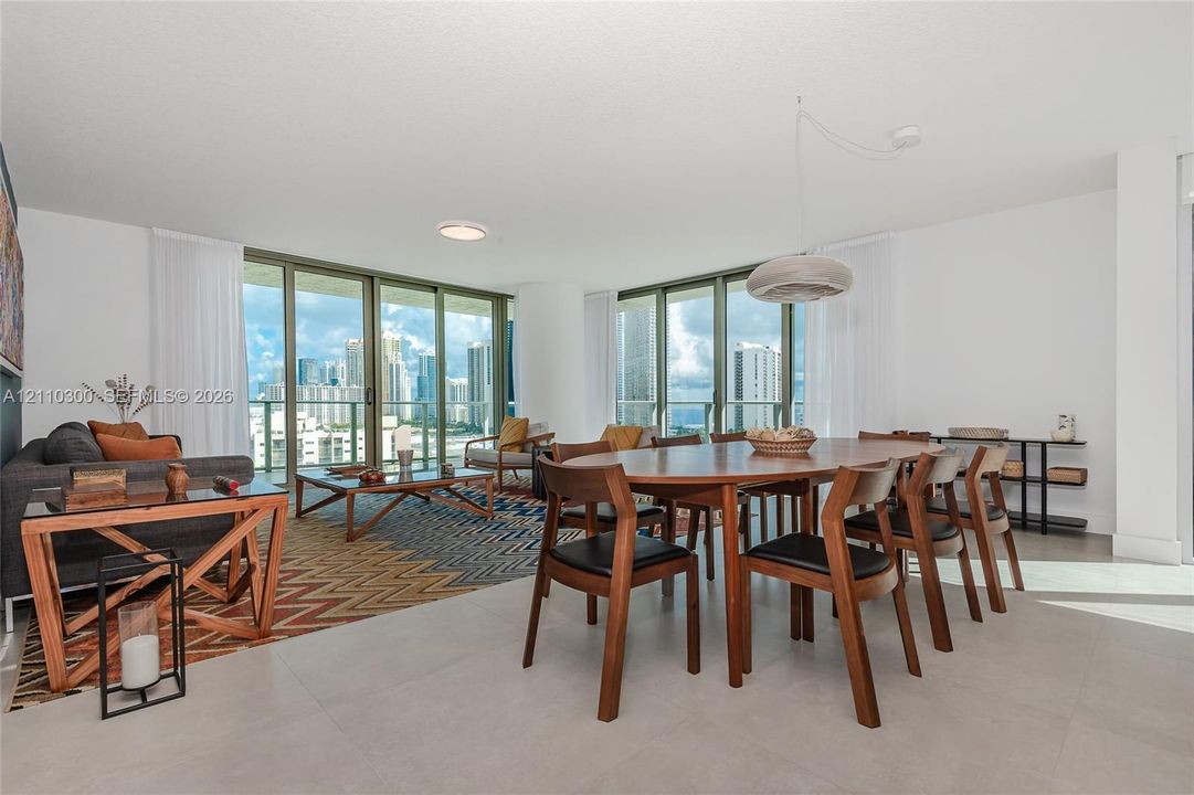 Open-concept living area featuring floor-to-ceiling glass walls, large-format tile flooring, and integrated overhead lighting
